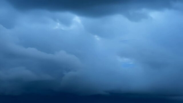 Brooding storm clouds loom over a vast, dark body of water. Intense blue hues dominate, creating an eerie, foreboding atmosphere. Layered clouds hint at impending turbulence.	