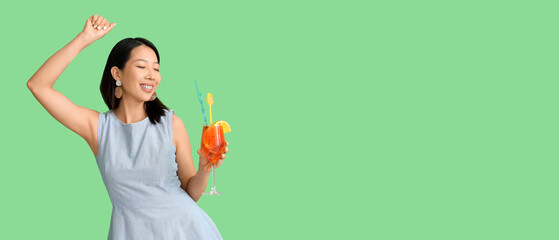 Beautiful young Asian woman with glass of tasty aperol spritz cocktail on green background