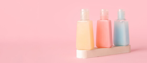 Plaster podium with bottles of different cosmetic products on pink background