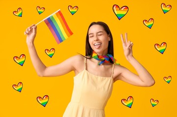 Beautiful young woman with LGBT flag showing victory gesture on yellow background