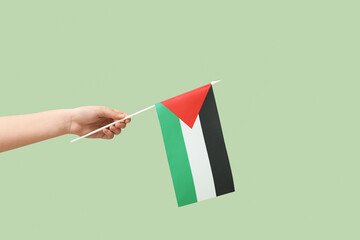 Female hand with flag of Palestine on green background