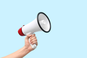 Female hand with megaphone on blue background