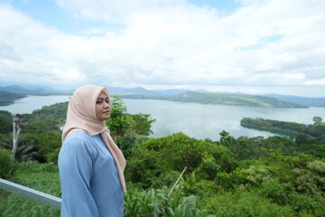 Fototapeta premium Muslim woman standing enjoying the beautiful panorama of Bollangi Hill in the morning