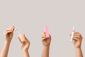 Female hands holding bottle and pen of cuticle oil with buffer on white background
