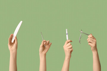 Female hands with cuticle oil pen, nail file and cutter on green background