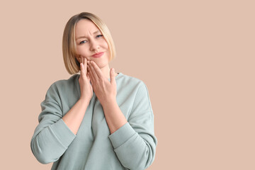 Woman with tooth ache on beige background