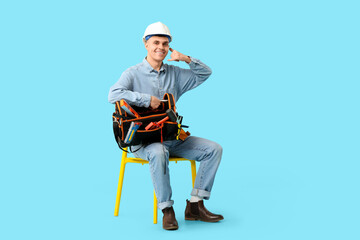 Young male electrician with tool bag showing 