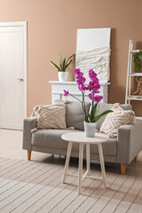 Interior of stylish living room with sofa and orchid flower on table