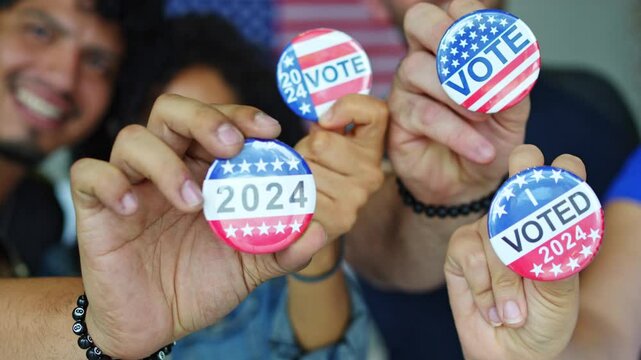 diverse group of smiling friends holding 2024 Vote election I voted buttons or pins at a US election polling station. In the background, american flag at the background, democracy in America USA