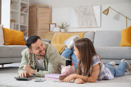 Father and his daughter with piggy bank counting money at home. Tuition fees concept