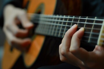 Obraz premium Detail shot of musician's hands playing a classical guitar, with a focus on the finger placement