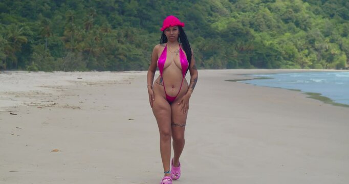 A girl in a thong bikini revels in a sunny day on a Caribbean beach in Trinidad.
