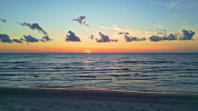 Sunset over the sea with a beautiful sky and calm waves at Kāpas pie Irbes upes ietekas