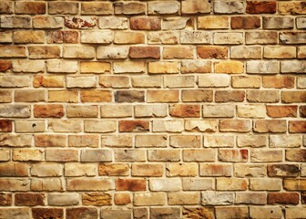 Fototapeta premium Weathered old brick wall with a warm cream color tone, uneven texture, and subtle cracks, adding a touch of vintage charm to any setting.
