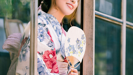 縁側でうちわを持つ浴衣姿の日本人女性