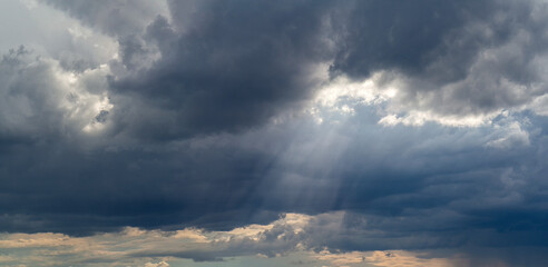 Heavenly landscape. The sun's rays break through the dark clouds. Sky background with clouds and sun rays.