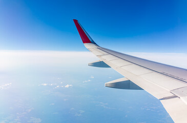 Fototapeta premium View from the airplane window at a beautiful cloudy sky and the airplane wing