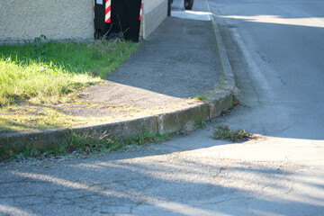A curb is seen at the side of a road, covered with grass. This image includes keywords like automotive tire, road surface, infrastructure, asphalt, sidewalk, and vehicle
