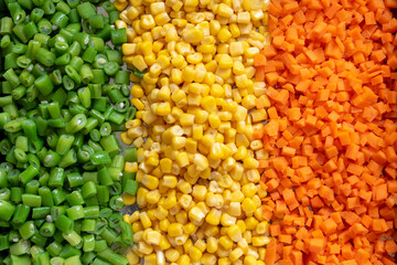 Assorted vegetables (carrots, corn and green beans) arranged in rows