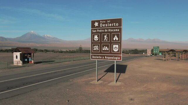 Aerial: Drone Panning Shot Of Sign Board At Roadside In Semi Arid Desert On Sunny Day - Atacama Desert, Chile