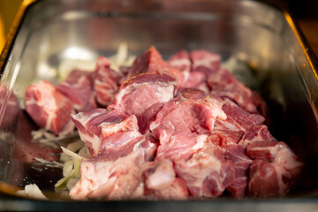 close-up in an iron container on bed of onions lie pieces of fresh meat barbecue time professional cooking the process of marinating meat