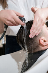 Naklejka premium Barber shampooing washing a male clients head in the sink.