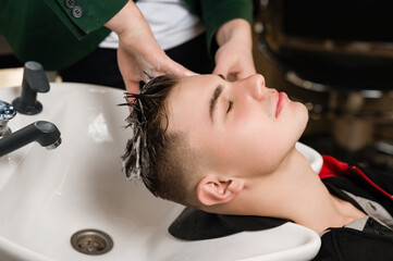 Fototapeta premium Barber shampooing washing a male clients head in the sink.