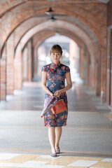 Fototapeta premium Young Taiwanese woman in her 20s wearing a blue cheongsam, strolling through a cultural district in Wanhua, Taipei, Taiwan