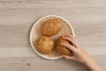 A woman take the potatoes on the table. テーブルの上のジャガイモを取る女性	
