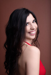 Fototapeta premium Beautiful young woman with long black hair smiling over shoulder