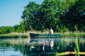 Jezioro z łódką i rybakiem łowiącym ryby © Franciszek