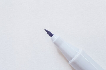 tip of blue marker laying on blank sheet of sketch book