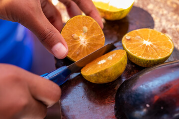 someone cuts oranges with a thin knife or cutter on the table to make juice
