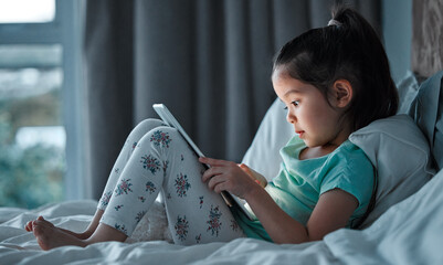 Online, tablet and little girl on bed for education, learning or child development in bedroom....