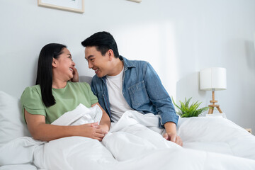 Asian mature couple sitting on bed after wake up together in house.