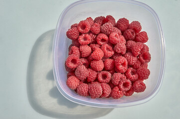 Top view of raspberries in a container on a white background
