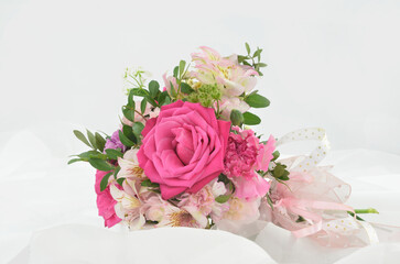 Wedding bouquet of pink flowers (roses) lying on white tulle - light background. Affection.