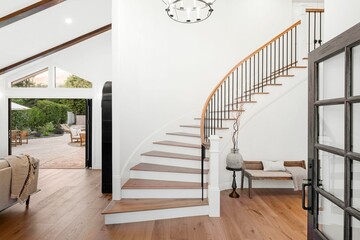 home interior with a curved staircase, wooden floors, and a view of the patio through open doors.