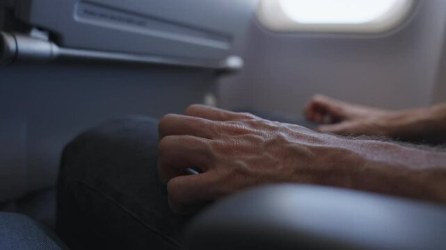 Fear of flying. Man on a plane grips his seat, visibly terrified of flying. Concept of aviophobia or aerophobia. He taps his fingers nervously, anxious for a safe landing and fearing a crash.