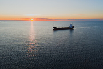 Naklejka premium Unloaded container ship in the Baltic sea st sunrise or sunset, photo view from a drone.