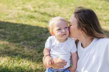 Fototapeta premium Female Toddler And Her Mother With Sunscreen On Face On Bright Green Grassy Garden Background. Concept Of Protecting Baby's Skin From Uv Rays. Concept Of Skin Cancer Prevention And Aging.