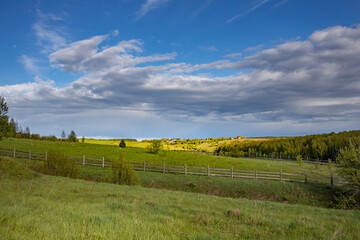 A large, open field with a fence in the foreground