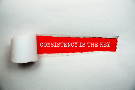 Consistency Is The Key message written on red paper with torn paper background