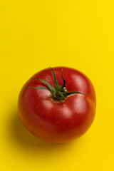 Fresh red tomato on yellow background. Top view.