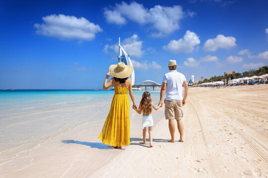 A tourist family on summer holiday time walks down a beautiful city beach in Dubai, United Arab Emirates