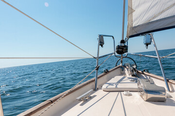 Luxury cruise on a sailing rigged yacht under a genoa sailing in a light wind during the regatta. Yachting as a luxury sport and great vacation. View from the deck to the bow, mast, sails.