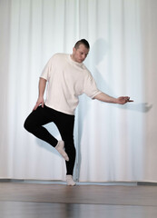 Fototapeta premium Home workouts in yoga poses. A man performs sports dance exercises with his legs and arms. Pilates stretching