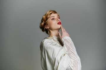 A woman in a white dress and pearl necklace gazes upwards, her hand gently touching her chin.