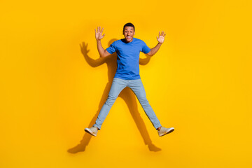 Fototapeta na wymiar Full length photo of handsome young guy jump wave hands dressed stylish striped garment isolated on yellow color background
