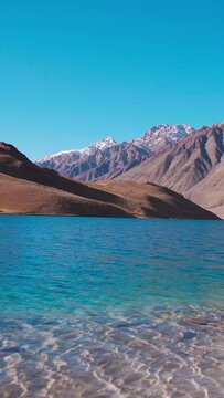 Vertical shot of beautiful Chandratal lake during summer in Spiti Valley, Himachal Pradesh, India. Nature and tranquility. Moon lake in Himalayas. Clear blue water lake surrounded by mountains.